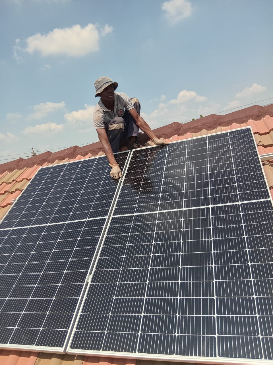 Solar panel installer fitting a PV module on tile roof